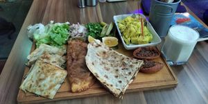 Plate with lahmacun, potatoe salad, some kind of friend pastry with soy filling, some pastry with spinach and Ayran made from cashew. at Veganarsist Kadıköy - Osmanağa in Istanbul