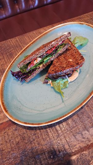 Vegan sandwich with toasted rye bread, chili hummus, cheese-free pesto, salad, semidried tomatoes and homemade fermented fennel (optional)  at Café Parforce in Klampenborg