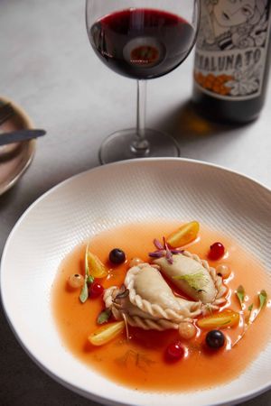 Polish cuisines, pierogi filled with artichoke and vegan dulce cheese, on a datterini tomato consommé. at Oliveira Kitchen in East London