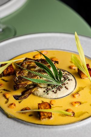 Our main course: a confit artichoke with hemp seeds, hemp leaves, corn leche de tigre, corn tempeh, and corn sprouts at ANOAH in Zurich