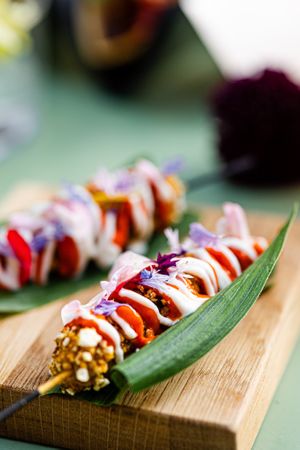 Our BBQ corn skewer from a local farmer friend, coated in popcorn, topped with ajvar and edible flowers at ANOAH in Zurich