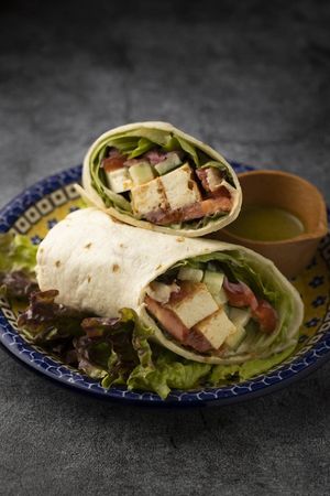 Available on Wolt.com - sweet & spicy harissa atsuage tofu wrap with avocado, haloumi cheese, roasted red peppers, tomato, cucumber, lettuce & soy yogurt. (can be made vegan)  at Salam in Tokyo