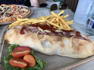 Vegan hot dog, vegan pizza in the background.  at Alkionis Sports Bar & Grill in Rhodes