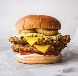 Double fillet special of the month burger with double crispy fillets, extra cheese, crushed avo, onion rings, tomatoes and homemade garlic mayo  at Huns in Leicester