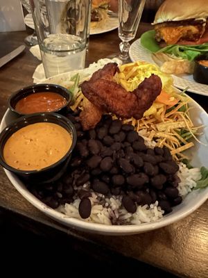Pow pow pow bowl with curtido, spicy white onions, tortilla strips, and maduros. Side of al pastor sauce and sunflower chipotle sauce.  at Hermanas Kitchen and Cocktails in Lindenhurst