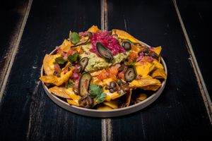 Home-made corn tortilla chips, puebla-style mole with black beans, cheddar sauce, guacamole, jalapenos, pico de gallo and pickled onion at Vrutal - Poblenou in Barcelona