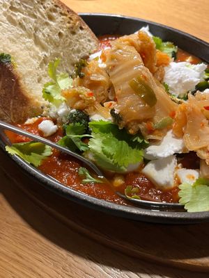 Vegan shakshuka with cilantro, champignons, feta and focaccia, + extra kimchi. at Kolm Tilli in Tartu