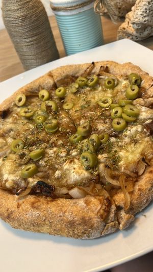 Pizza vegana con harina integral , queso vegano , aceitunas y cebolla caramelizada   at Kinoa in Malaga