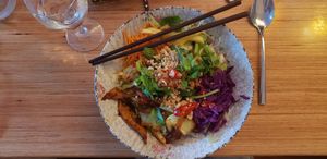 Flavorful noodle bowl with many vegetables, herbs and "duck", and noodles and sauce at the bottom. at Well Being in Cologne