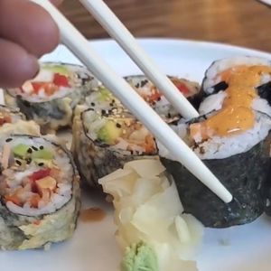 Salmon roll (holding with chopsticks) at Tenon Vegan Sushi in Toronto