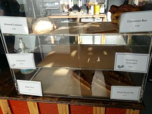 Various croissants, cinnamon bun, apple slice, and maple pecan pie; many sold out by midday. at The Well Bean Co in East London