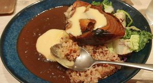 Curry with brown rice, half a roasted onion and melty vegan cheese at RUCY+R 横浜ジョイナス店 in Yokohama