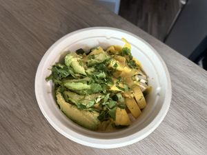 Vegan coconut curry veggie  bowl with added tofu and avocado, served to-go in a compostable bowl  at Mixed Greens in Santa Clara