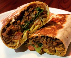 The Cheeseburger Burrito- Seasoned TVP, juicy tomatoes, crispy lettuce, chopped onions and pickles grilled in a tortilla. (Vegan, gf tortilla available)  at Spacecat V-stro in Ferndale