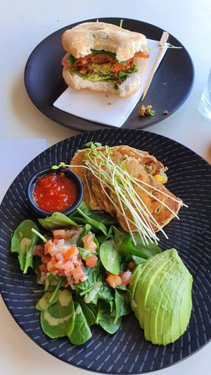 Vegan corn and zucchini fritters with avocado, spinach, bruschetta mix & tomato chilli jam (front) & vegan roll with Chickpea and lentil patty, spinach, tomato, avocado & vegan bas at Lure in Port Douglas