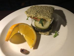 Raw American burger : burger made with Brazil nuts, walnuts, sunflower seed, golden flax seeds, zucchini kale, chipotle pepper, avocado, served with raw coconut bread, tomato, oni  at Caravan of Dreams in New York City