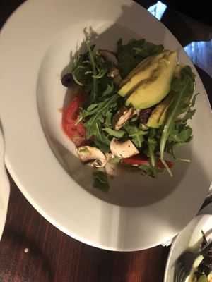 Raw pizzetta (gf) -pumpkin flaxseed crust, tomato marinara sauce, house cultured cashew kefir cheese, arugula, avocado, cherry tomato, olives, cremini mushroom, olive oil, salt   at Caravan of Dreams in New York City