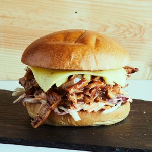 Tangy BBQ pulled Jack fruit and grilled pineapple chunks on vegan brioche bun, cheese, and our house pomegranate molasse slaw. at Leaf Lovers in Birmingham