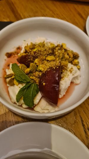 Krem sernikowy z wanilią i pistacjami, śliwki gotowane w wermucie, limonka, mięta at Peaches Gastro Girls in Warsaw