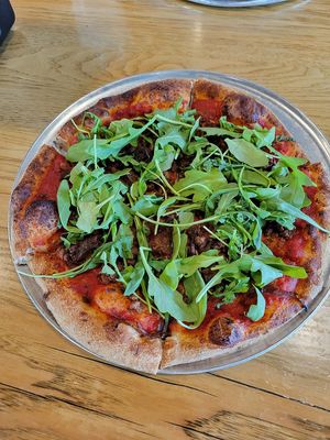Make your own pizza with arugula, vegan sausage, and grilled onions at Pinthouse Pizza in Austin