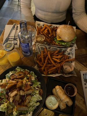 Very amazing sweet potato fries, cheese burger, Greek salad with chicken slices and dough rolls filled with cheese  at Mad Mad Vegan - Lavapiés in Madrid