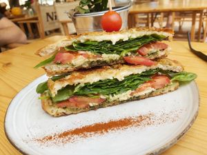 Vegan mafia sandwich with focaccia bread, filled with melted vegan cheese, lots of spinach, some pesto and fresh tomatoes at Nibs Healthy Bar in Menorca