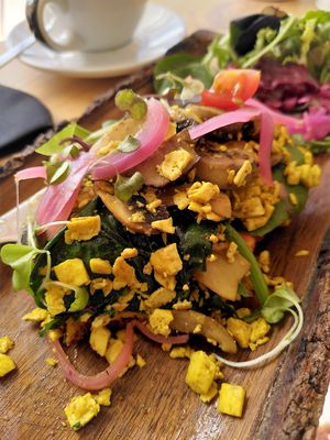 vegan Scrambled eggs with tofu and curry, spinach, mushrooms, pickled onion, homemade turmeric bread and "ramallet" tomato. at MaiMai Surf Bar in Mallorca
