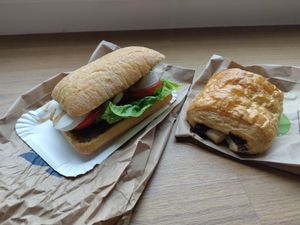 Ein Schokocrossaint und ein belegtes Brötchen mit veganem Mozzarella, Tomaten und Pesto. at denn's BioMarkt - Luegallee in Dusseldorf
