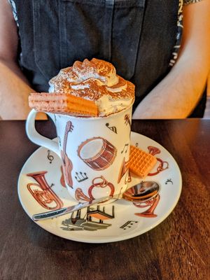 Vegan hot chocolate with whipped cream and pink wafers at The Music Cafe in Stratford-upon-avon