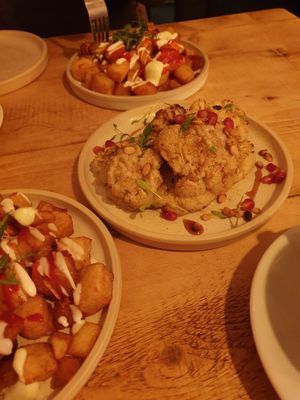 Patatas bravas and cauliflower in tahini sauce with pomegranate seeds on top at Vegan Tapas in Heswall