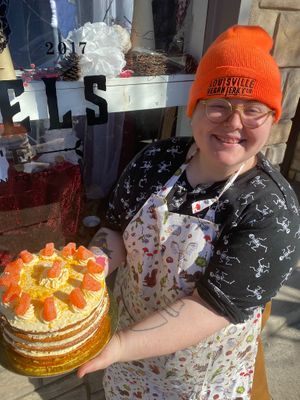 The owner/ baker holding an orange cream cake  at The Indignant Platypus in Louisville