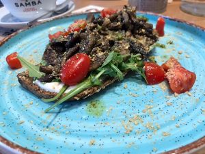 Open Mushroom Pesto Sandwich: Whole grain bread with basil pesto, mushroom gyros, vegan parmesan, arugula salad, cherry tomatoes and basil pesto at Rubik's in Thessaloniki