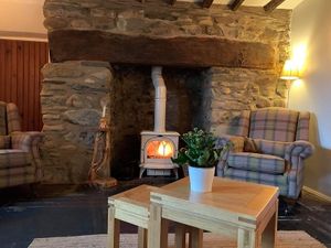 The lounge has the lovely inglenook fireplace with a wood burning stove as the focal point There is a large 3 seater sofa and 2 armchairs. at Pen Bryn Twrw at Idlewild Animal Sanctuary in Conwy