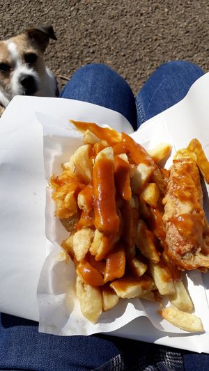Battered sausage, chips and curry sauce. at Barnacles in Llandudno