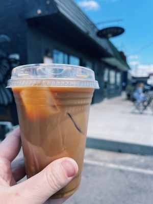 Exterior of building, takeaway container with an iced dirty chai with oat milk. at Elegy Coffee in Nashville