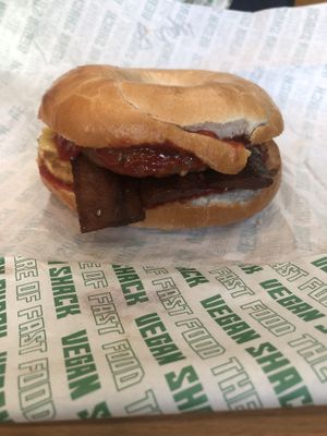 Bagel with bacon, tofu, ketchup and a cheeky sausage patty added extra  at Vegan Shack - Piccadilly Gardens in Manchester