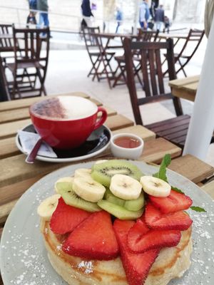 Pancake with fruits and maple syrup, almond cappuccino at O Croisant in Coimbra