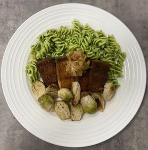 Marinated Tofu steak topped with caramelized onions over a gluten free pasta that has been tossed in a light chimichurri sauce with a side of roasted brussel sprouts. at P2F Meals in Fort Myers