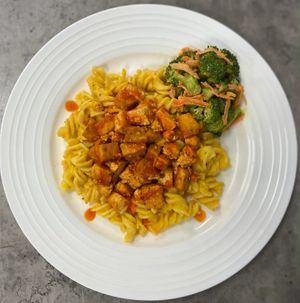 Baked Buffalo Tofu bites served over gluten free pasta that has been tossed in our plant-based cheese sauce, served with a side of our cashew ranch broccoli slaw. at P2F Meals in Fort Myers