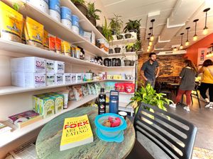 Seating area Roots 2 Rise, bookshelves, grocery "What the Fork are you eating?"My Tupperware with a R2R cookie, carrot muffin,Yeti cup with Chai tea, sugar & BLK lychee 7/24/2022 at Root 2 Rise in Pleasantville