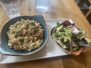 Vegan Mac & cheese with tempeh bacon, breadcrumbed onions and a spinach pesto sauce. Accompanied with a small salad   at Hendersons in Edinburgh