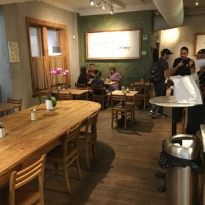 Inside: note community table and separate tables. at Le Pain Quotidien - Madison Ave in New York City