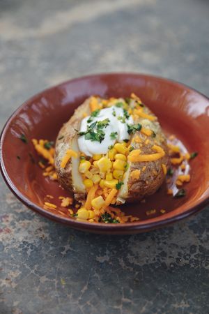 Cantinflas: baked potato with melted garlic butter, cheese and corn, topped with sour cream and spring onions. (Vegan option available) at Papa Deluxe Baked Potato & Salad Bar - Tulum in Tulum