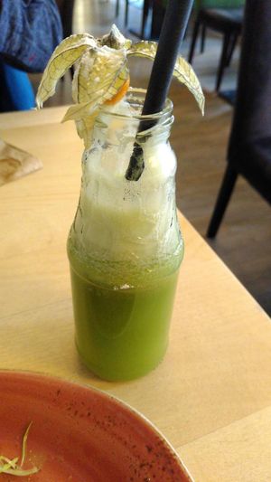 Green smoothie served innovatively in an open bottle, nicely decorated with physalis. at Max Pett in Munich