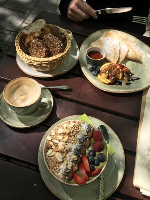Top: basket of fresh bread, pancakes with fruit and syrup
Middle: cappuccino with soy milk
Bottom: açai bowl at Max Pett in Munich