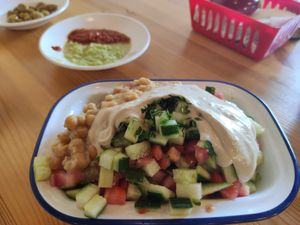 Freshly cut salad topped with tehina and humus grains at Humus Nechama in Haifa