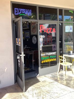 Signage on restaurant door promoting vegan pizza at University Pizza Company in Riverside