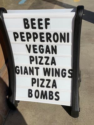 Rolling sign promoting vegan pizza at University Pizza Company in Riverside
