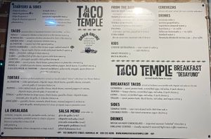Menu on the building. (V) is vegan. Nov. 1 2022. at Taco Temple in Asheville