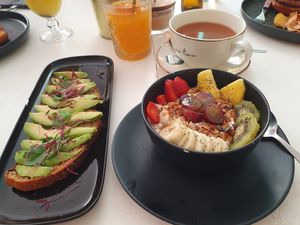 Avocado toast, yoghurt with fruit and granola, orange juice and tea - vegan menu option at Break Sé in Lisbon